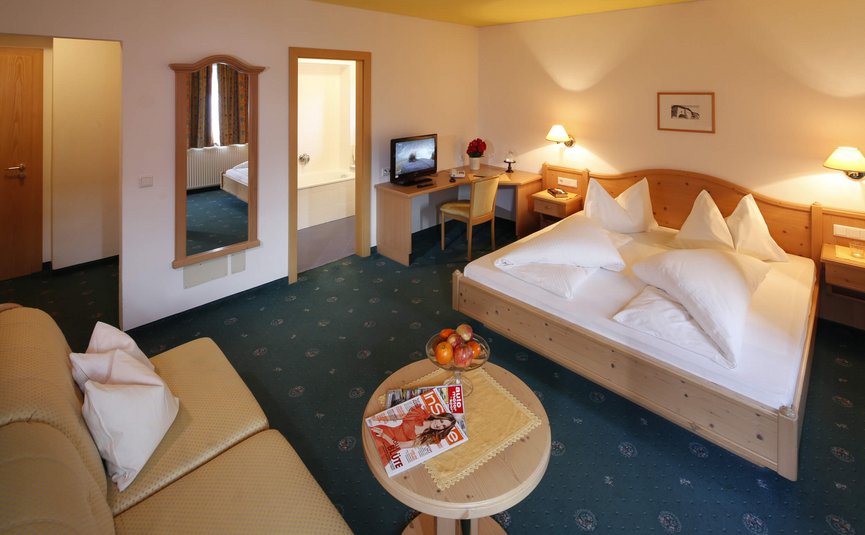 Hotel am Reschensee *** © The Dilitz Company GmbH Gemütliches Hotelzimmer mit Doppelbett, Sofa, Schreibtisch und Badezimmer
