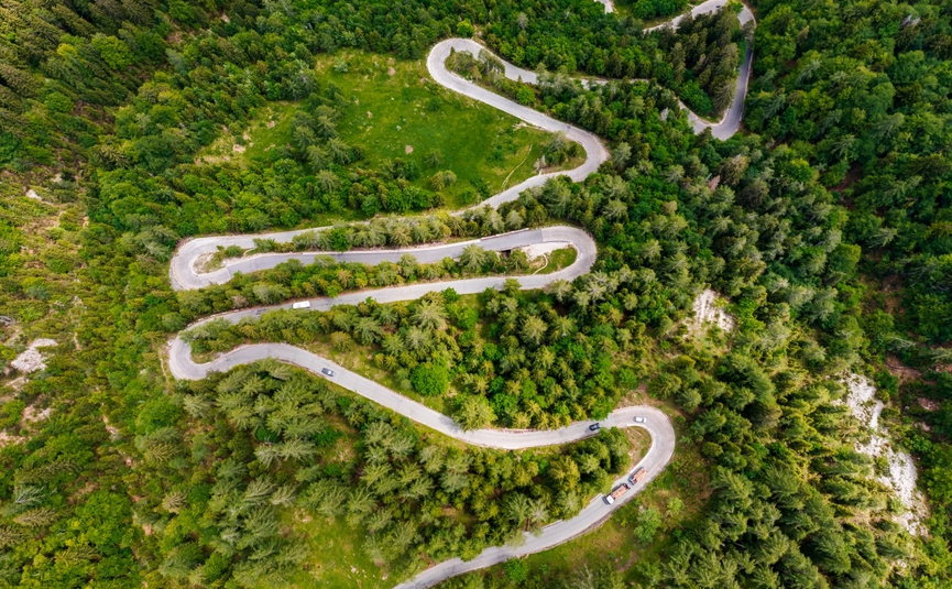 Kočevje Wildernis Ontdekkingsrit Luchtfoto van een kronkelende bergweg door dicht groen bos