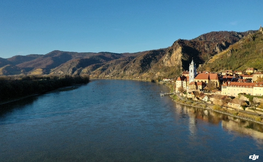 Fluss mit Dorf und Bergen bei klarem Himmel