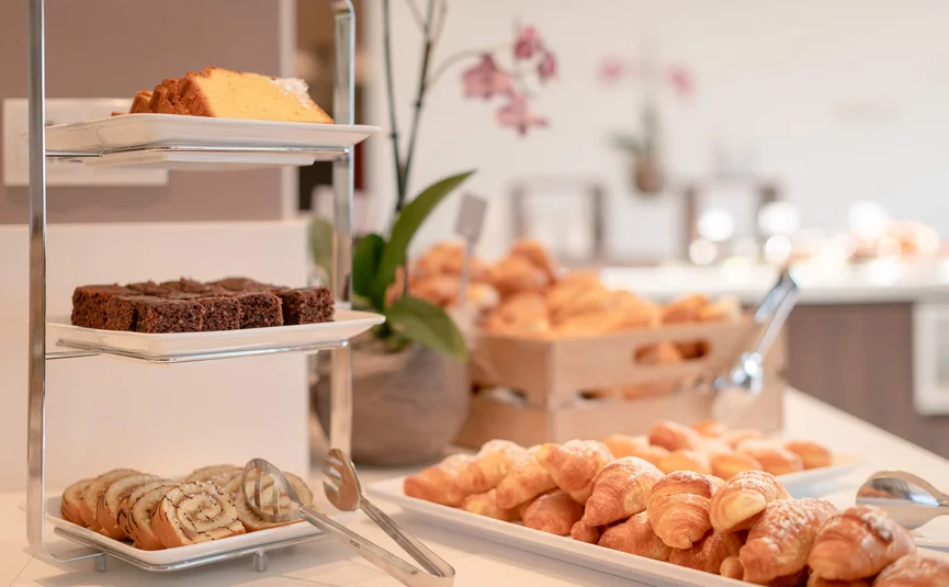 Assorted pastries on a buffet including croissants and cake slices