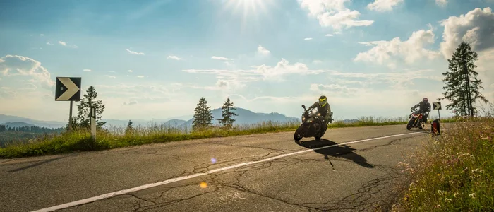 Two motorcycles riding on a sunny winding mountain road