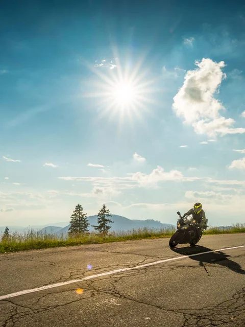 Two motorcycles riding on a sunny winding mountain road