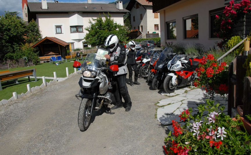 Freiheit auf zwei Rädern an 7 Tagen - Grosse Tour Motorradfahrer lesen Karten neben mehreren geparkten Motorrädern vor Häusern