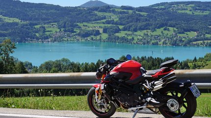 Attersee – Salzkammergut © Armin Hoyer Rotes Motorrad auf Bergstraße mit See und Hügeln im Hintergrund