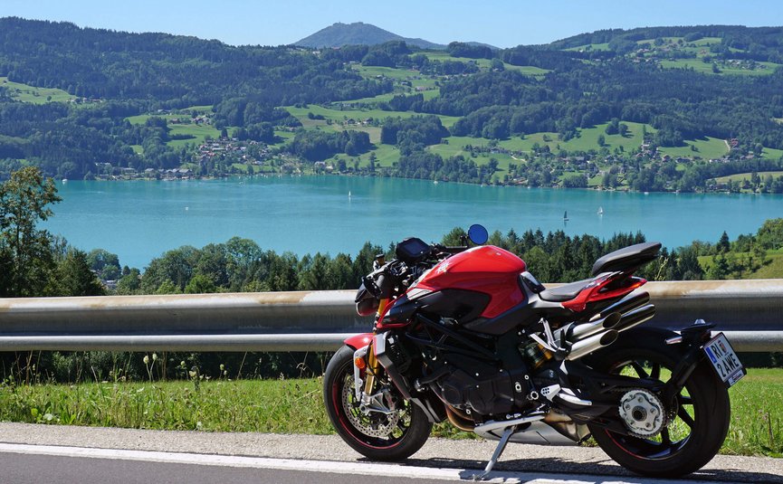 Motorradurlaub am Attersee – Salzkammergut © Armin Hoyer Rotes Motorrad auf Bergstraße mit See und Hügeln im Hintergrund