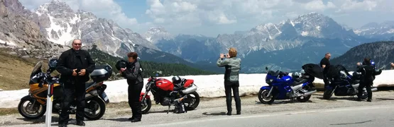 Motorcyclists stopped on mountain road with snow and clear sky