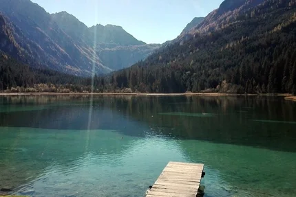 Wooden dock on clear mountain lake with forested mountains in background