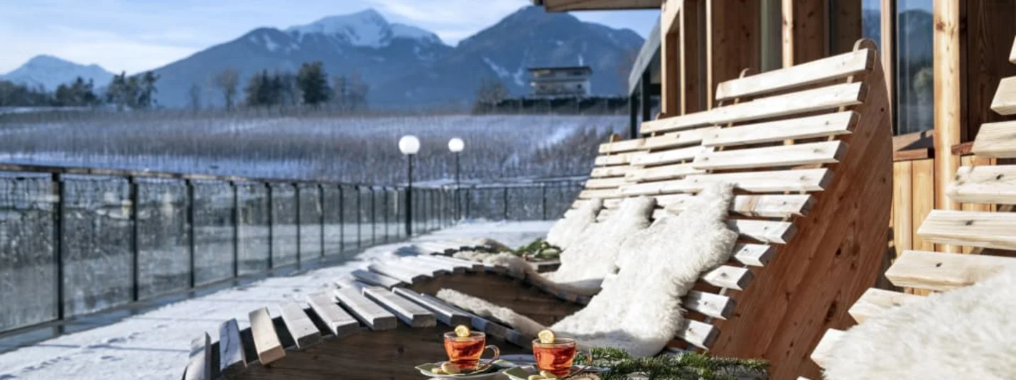 5=4 Wellness Power Package Houten ligstoelen met bont op terras met bergzicht en twee theekopjes