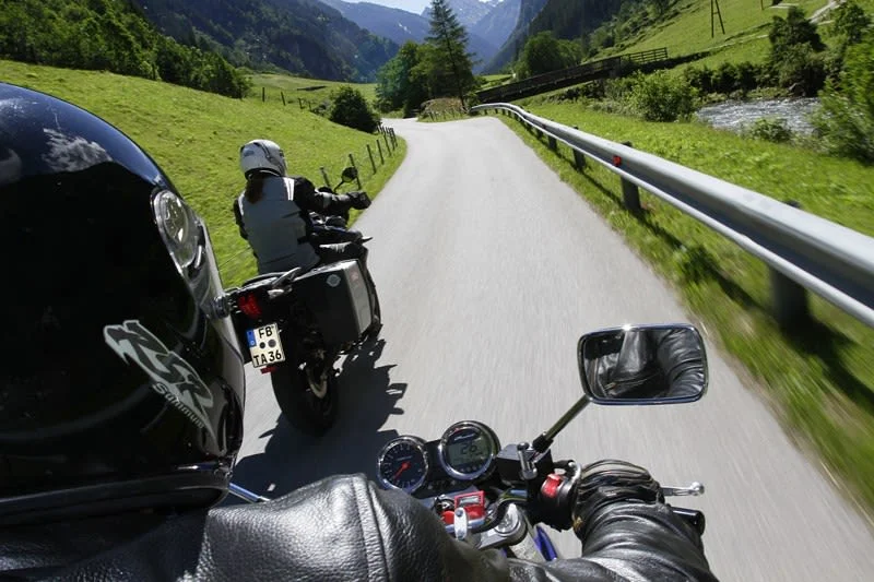 Zwei Motorradfahrer auf einer kurvenreichen Landstraße in den Bergen