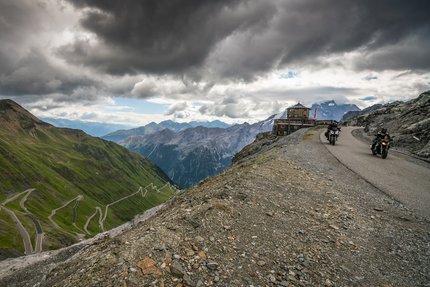 Motorradfahrer auf kurvenreicher Bergstraße mit dramatischem Himmel