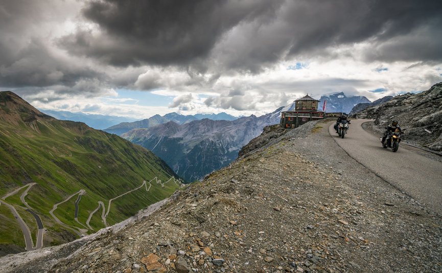 Motorradfahrer auf kurvenreicher Bergstraße mit dramatischem Himmel