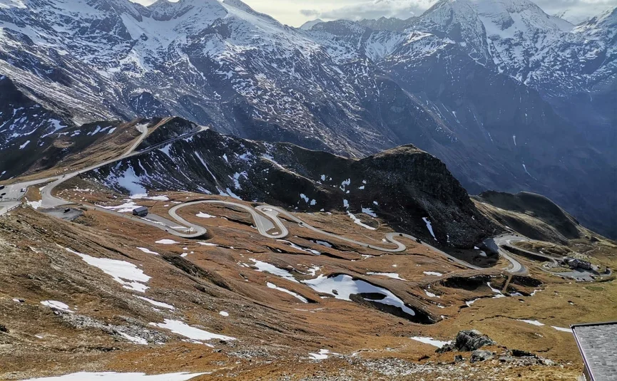 Großglockner Tour classic Tour 4 Winding mountain road with snow patches and snowy peaks in the background