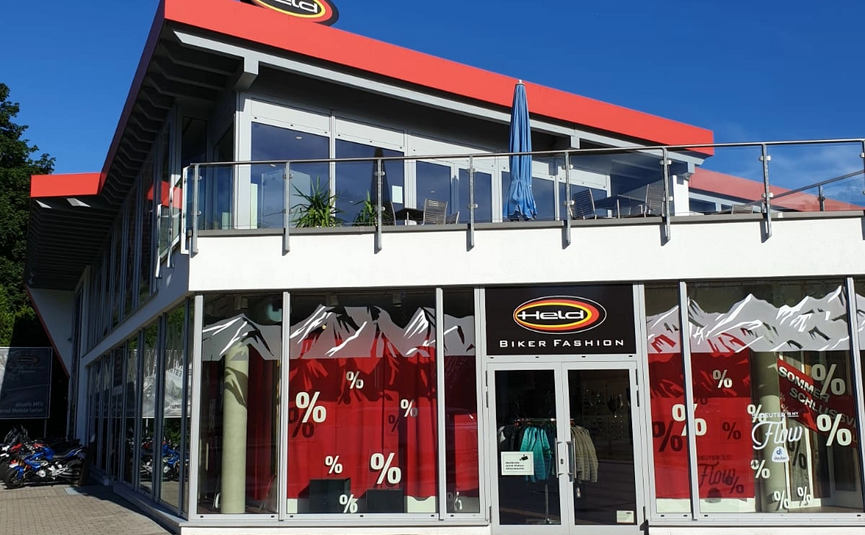 Modernes Gebäude mit großer Glasfassade und Held Biker Fashion Logo