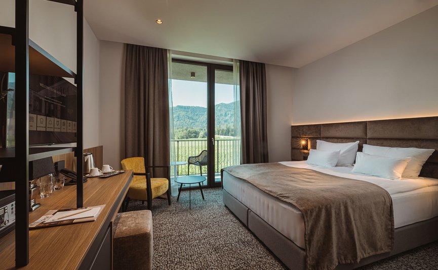 Modernes Hotelzimmer mit großem Bett und Bergblick durch das Fenster