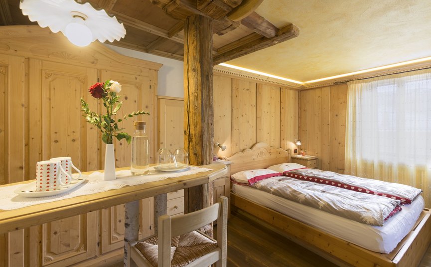 Gemütliches Holzschlafzimmer mit Doppelbett und kleinem Tisch mit Blumen