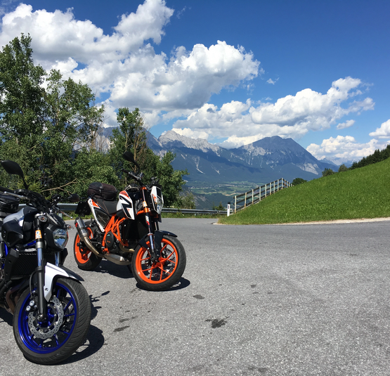 Zwei Motorräder auf Bergstraße mit Blick auf Berge und Wolken