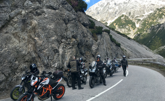 Motorradfahrer machen Pause auf einer Bergstraße neben Felsen