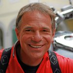 Motorvakanties in Zuid-Tirol en de Dolomieten © Kurt Resch Steineggerhof Lachende man in rood shirt voor een motorfiets