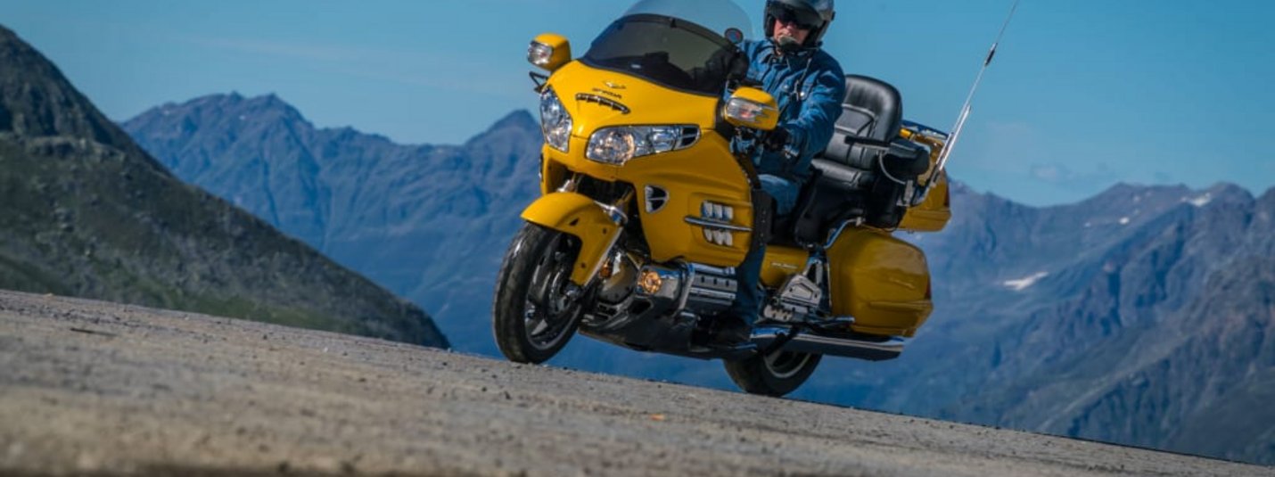 Volltreffer für Biker Mann auf gelbem Motorrad auf Bergstraße bei klarem Himmel