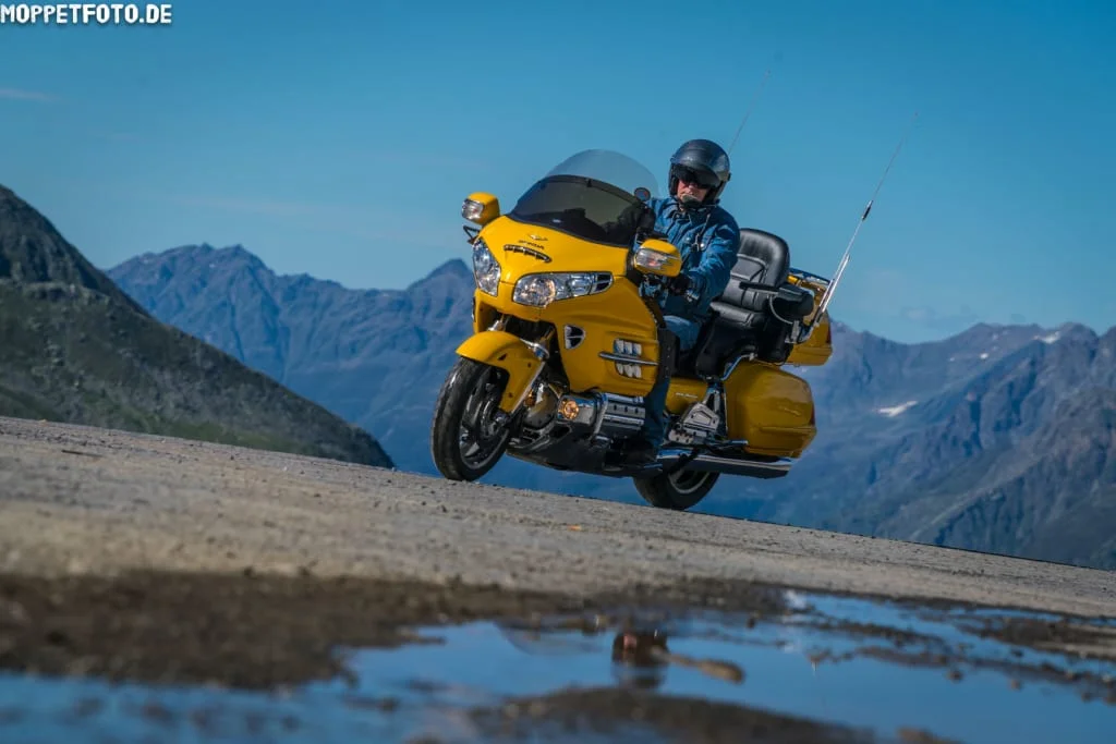 Mann auf gelbem Motorrad auf Bergstraße bei klarem Himmel