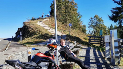 Rossfeld Panorama Tour Motorrad und Person sitzen auf Bank an Roßfeldstraße auf 1560 m Höhe