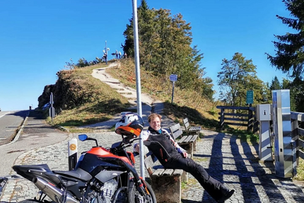 Motorrad und Person sitzen auf Bank an Roßfeldstraße auf 1560 m Höhe
