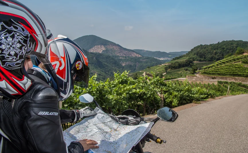 Hotel La Stüa **** © A. Monticelli Motorradfahrer mit Helm liest Karte auf ländlicher Straße mit Bergen