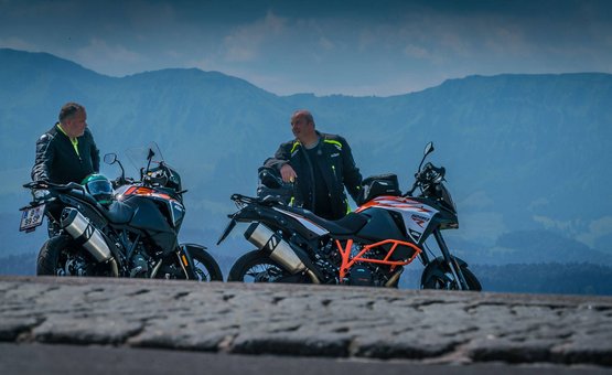 Zwei Männer mit Motorrädern auf einem Berg mit Bergkulisse