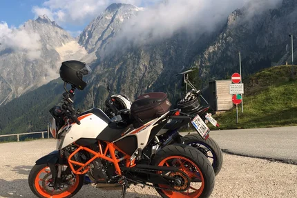 Motorcycles parked with mountain view and cloudy sky
