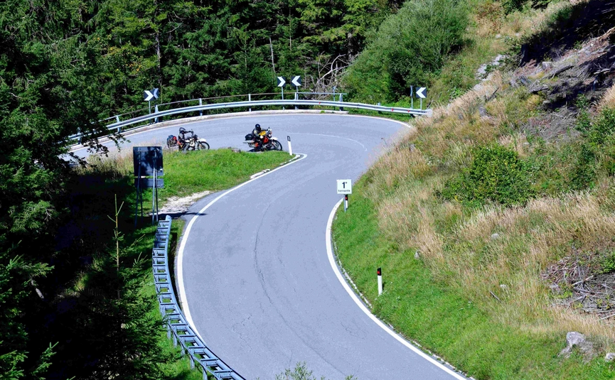 Emerald Soča River & Alpine Peaks Tour Motorcyclists on a sharp hairpin mountain road curve
