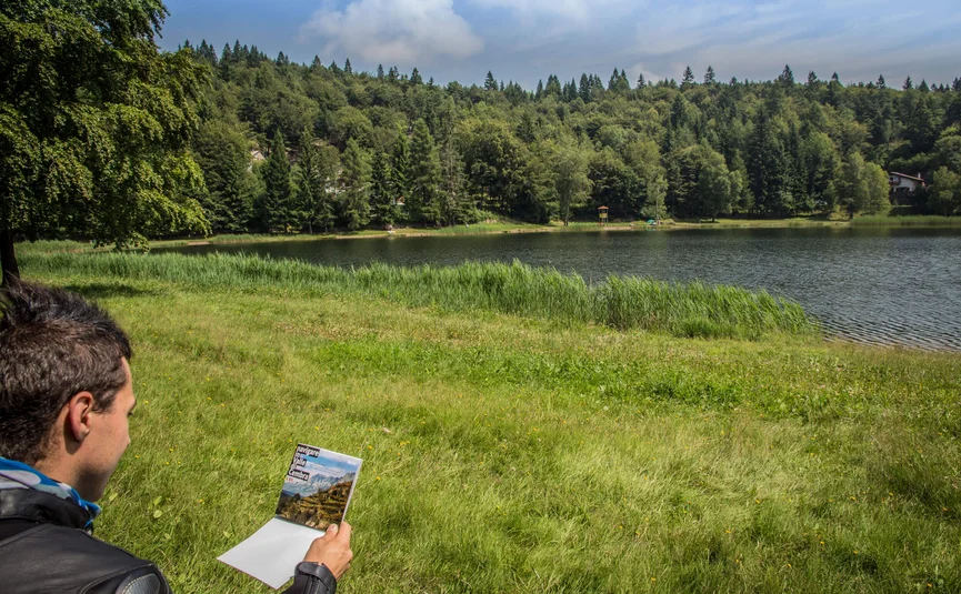 Motorradurlaub im Val di Fiemme © A. Monticelli Mann liest Karte am See mit Wald und Haus im Hintergrund