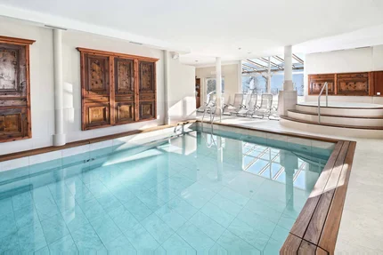 Innenraum mit klarem Innenpool und Whirlpool neben Holzpaneelen