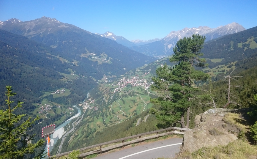 MoHo Schönauer Hof tour 13 Smugglers' tour Samnaun Mountain landscape with valley, river and road curve in foreground under clear sky