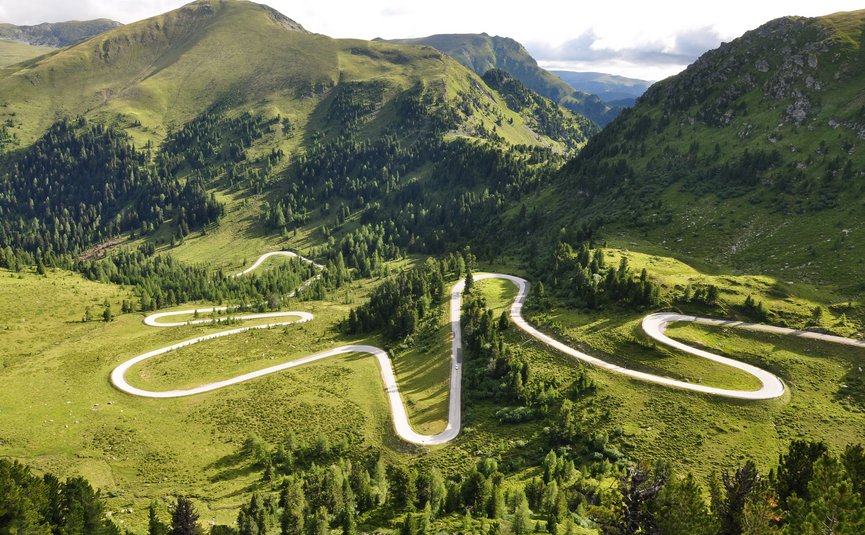 Serpentinenstraße in grünen, bewaldeten Bergen bei Tageslicht