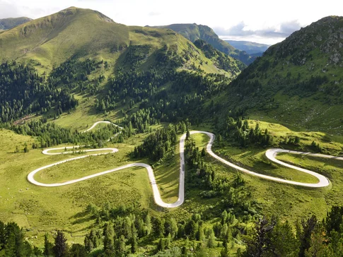 Serpentinenstraße in grünen, bewaldeten Bergen bei Tageslicht