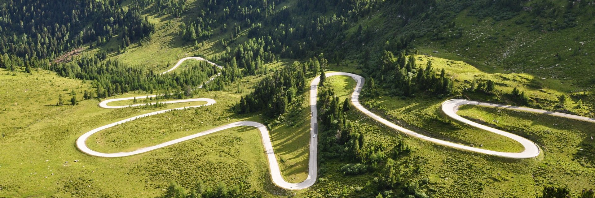 Erlebnishotel Kärnten-Mölltal ***S © Land Kärnten - Großglockner Hochalpenstraßen AG Serpentinenstraße in grünen, bewaldeten Bergen bei Tageslicht