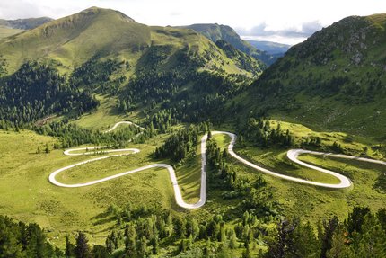Serpentinenstraße in grünen, bewaldeten Bergen bei Tageslicht