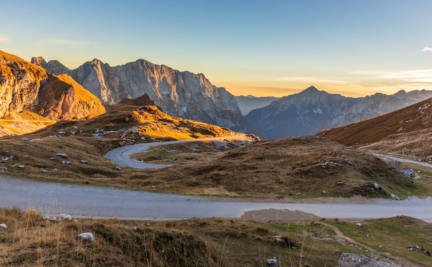 Kronkelende bergweg bij zonsondergang in de Alpen