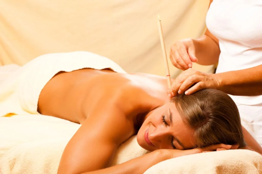 Frau entspannt bei Ohrenkerzenbehandlung während Massage