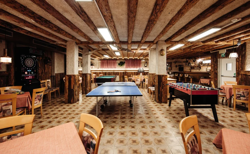 Spielzimmer mit Tischtennis, Kicker, Billard und Darts in rustikalem Raum