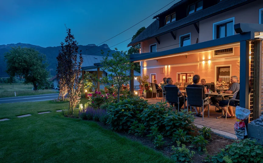 Evening garden party with friends on a terrace beside a house in nature