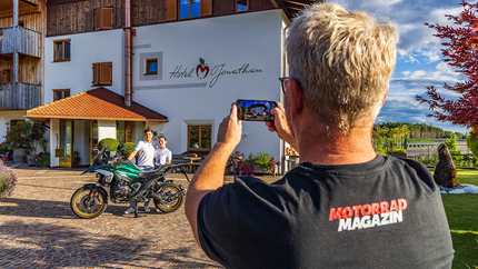 Persoon maakt foto van motorfiets met twee mensen voor Hotel Jonathan
