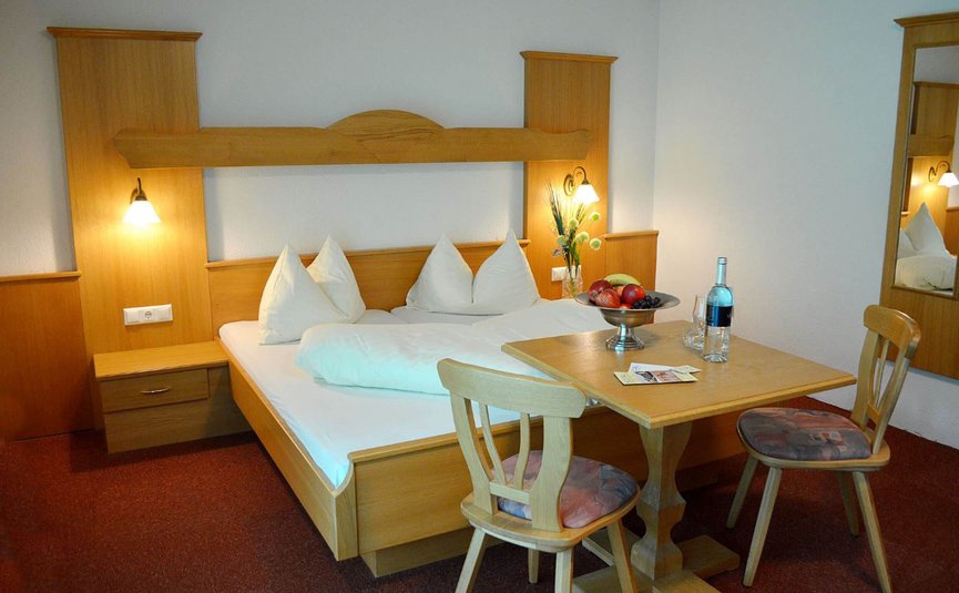 Erlebnishotel Kärnten-Mölltal ***S © Erlebnishotel Kärnten Mölltal Gemütliches Hotelzimmer mit Doppelbett, Holzmöbeln und kleinem Essbereich