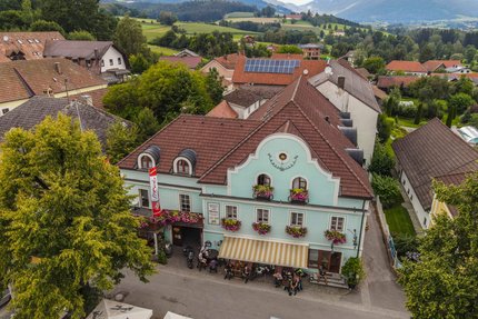 Gasthof Pension Drei Hacken © Alexander Seger Altes Gasthaus mit blauen Fassade und Blumen in einem Dorf mit Bergen im Hintergrund