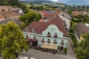 Sammelanfragen © Alexander Seger Altes Gasthaus mit blauen Fassade und Blumen in einem Dorf mit Bergen im Hintergrund