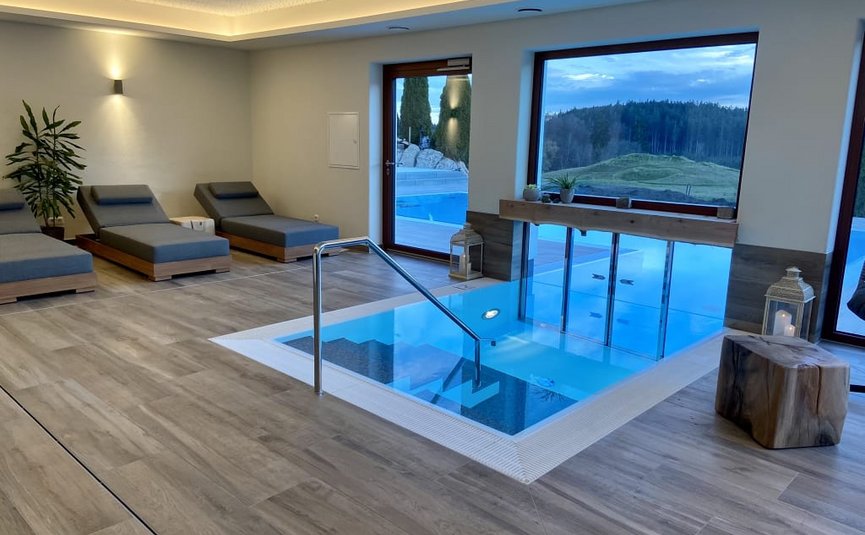 Modernes Spa mit Indoor-Whirlpool und Liegestühlen neben großen Fenstern