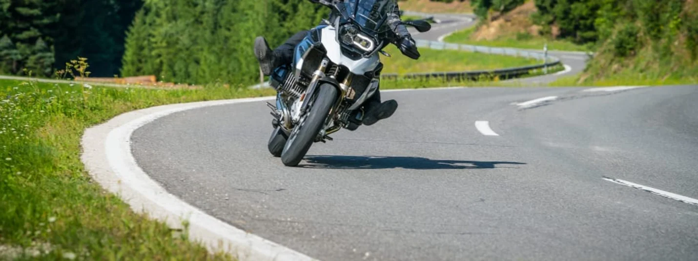KURVENQUICKY 2026/27 Motorrijder rijdt een bocht op een bergweg