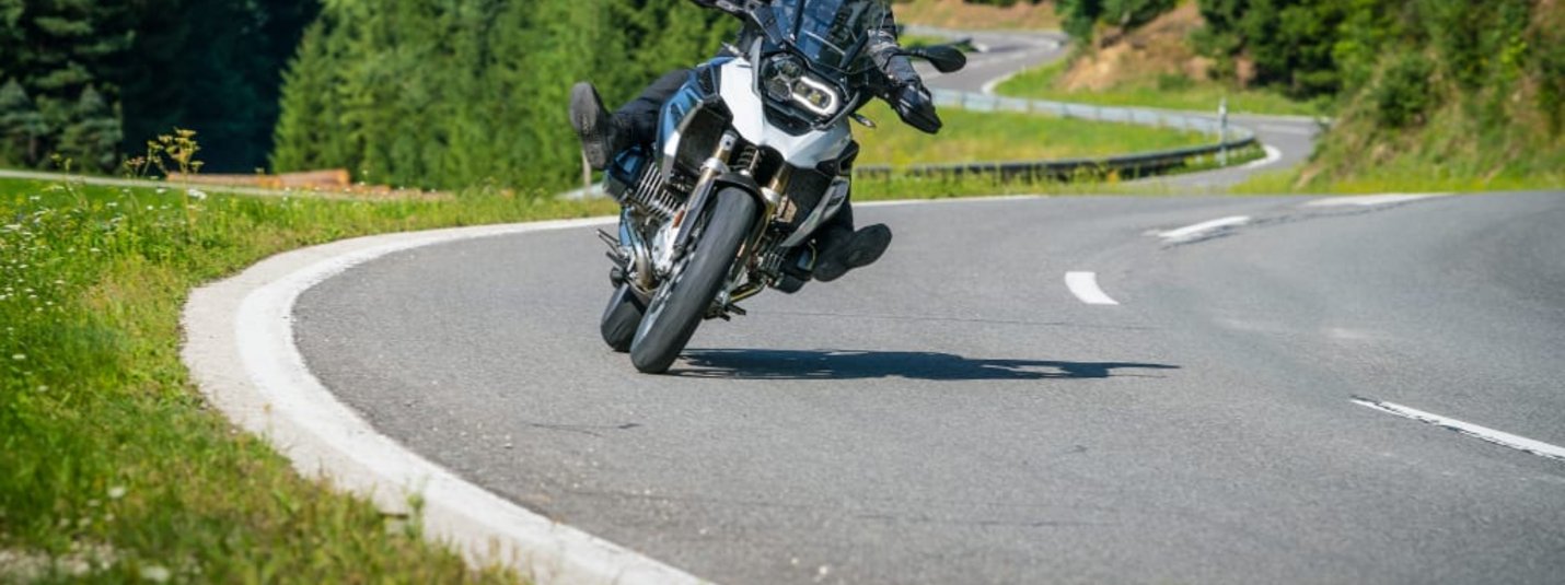 KURVENQUICKY 2026 Motorrijder rijdt een bocht op een bergweg