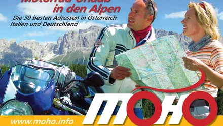 Geschichte der MoHo's Motorradfahrer mit Karte vor Alpenkulisse planen Urlaub