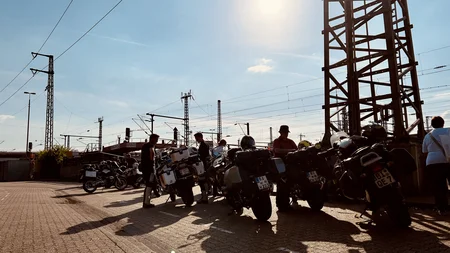 Motorradfahrer stehen neben ihren Motorrädern unter Sonnenlicht am Bahnsteig